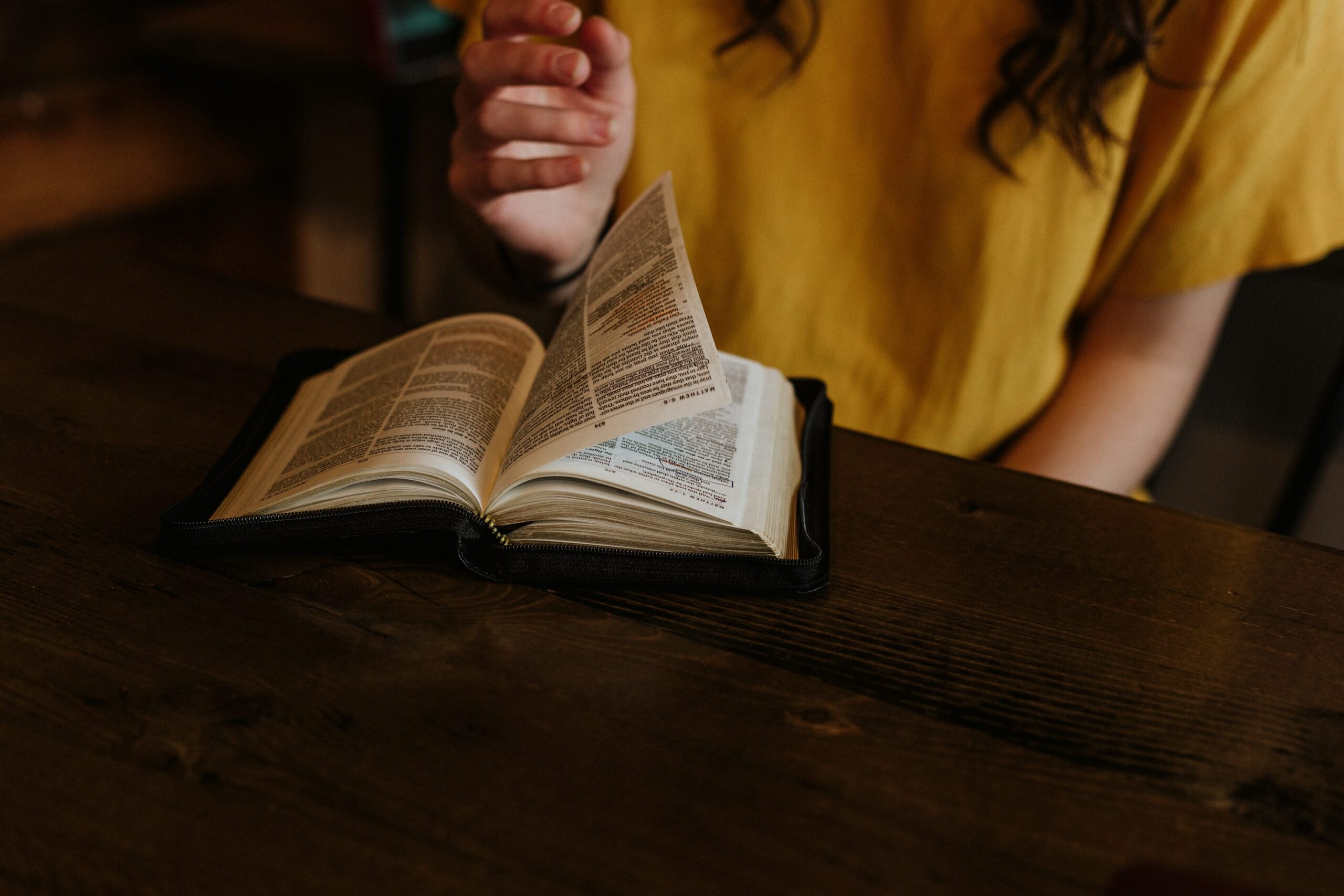 Persona leyendo la Biblia en una mesa de madera